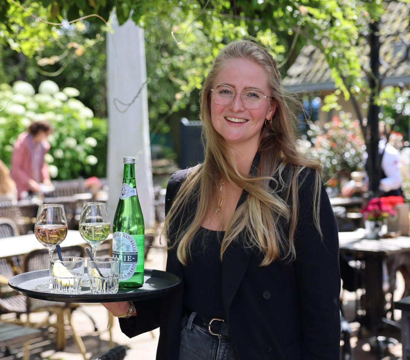 bedieningsmedewerker alana lacht en staat op het terras